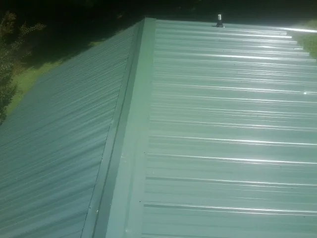 New green metal panels meeting at the ridge of a roof — Flat Roof Repair work by our crew in Wrightstown