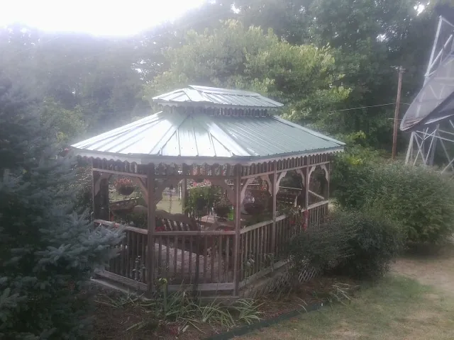 Green metal roof on a backyard gazebo surrounded by garden beds in Wrightstown