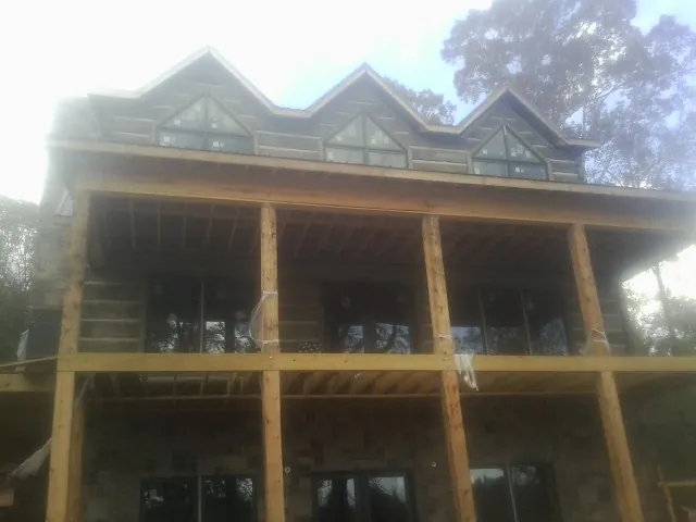 Dormers and porch framing on a large log home under construction — Roof Coating work by our crew in Wrightstown
