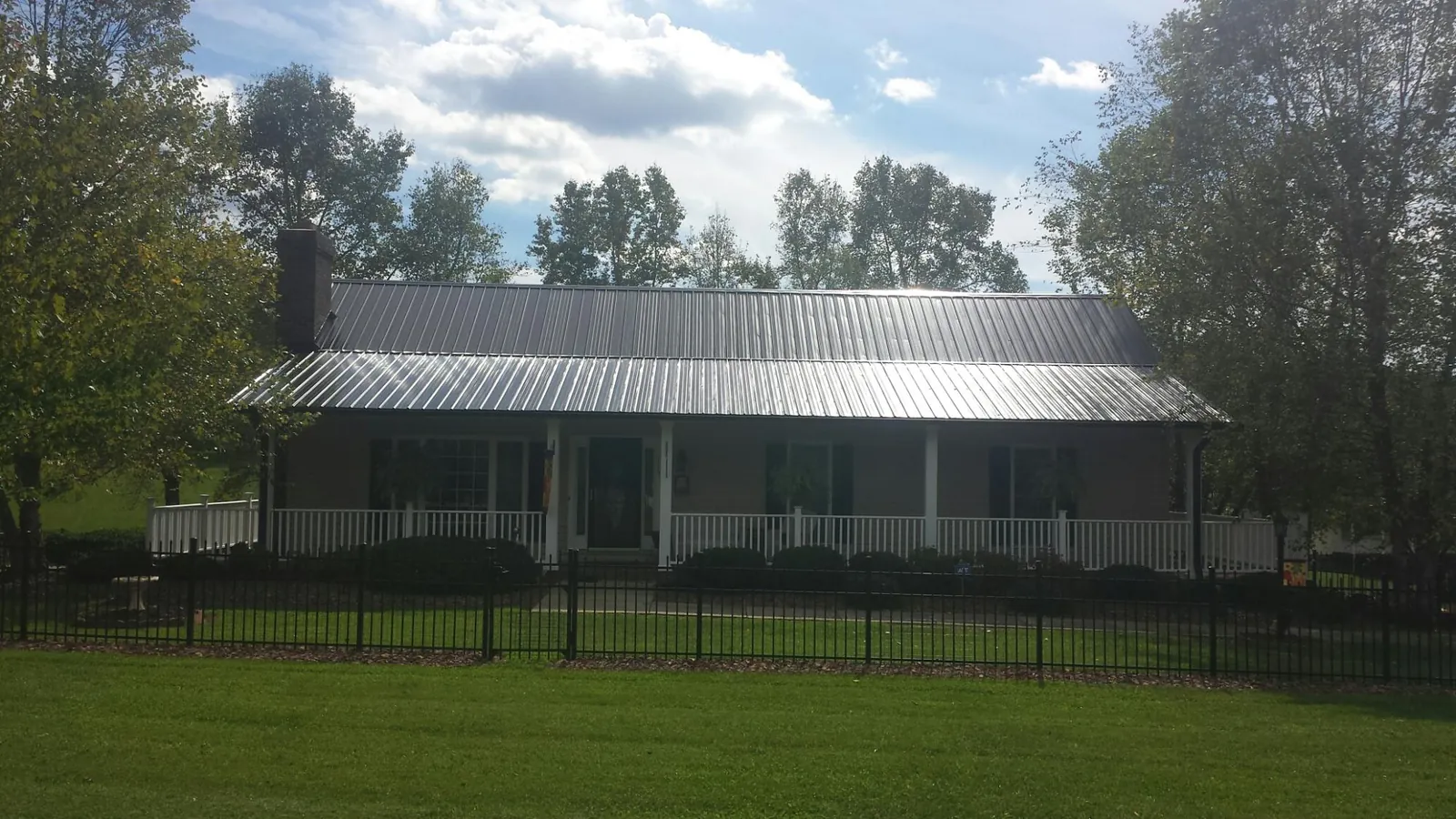 Gray metal roof on a brick ranch with a full width front porch — Gutter Guard Installation work by our crew in Wrightstown