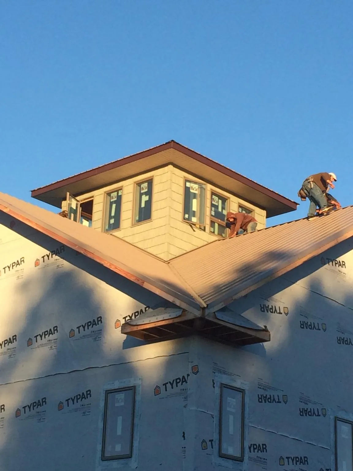 Roofers working around a rooftop cupola on a new metal roof at sunset — Roof Waterproofing in Wrightstown by Roofing Brothers